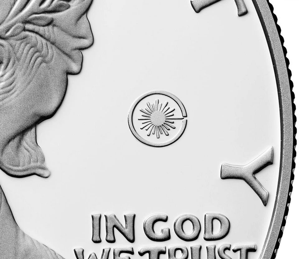 Close up of the American eagle silver dollar featuring the laser engraved privy mark consisting of a circle surrounding a radiant beam symbol.