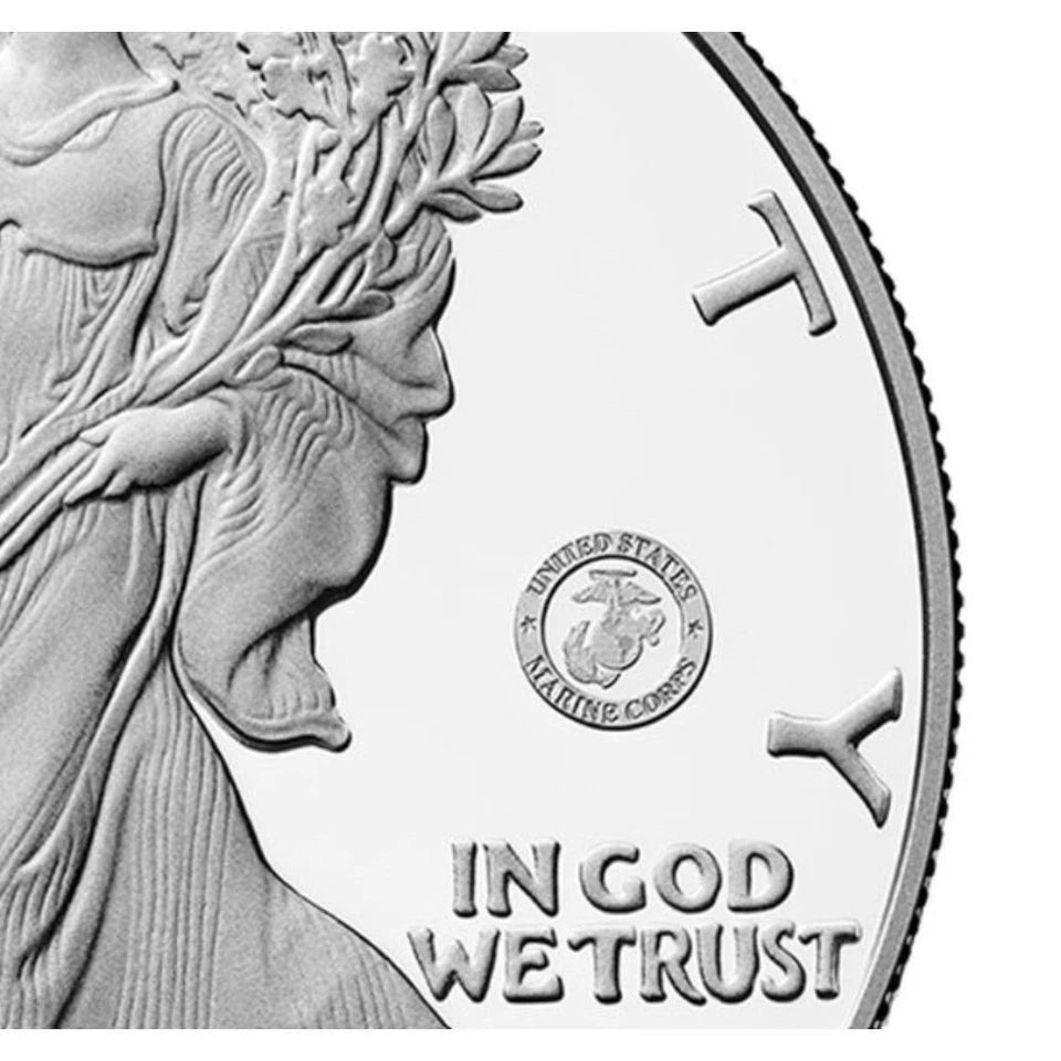 Close up of American eagle silver dollar featuring the US Marine Corps 250th anniversary privy mark consisting of a circular emblem that reads 'UNITED STATES MARINE CORPS' surrounding the Marine Corps insignia.